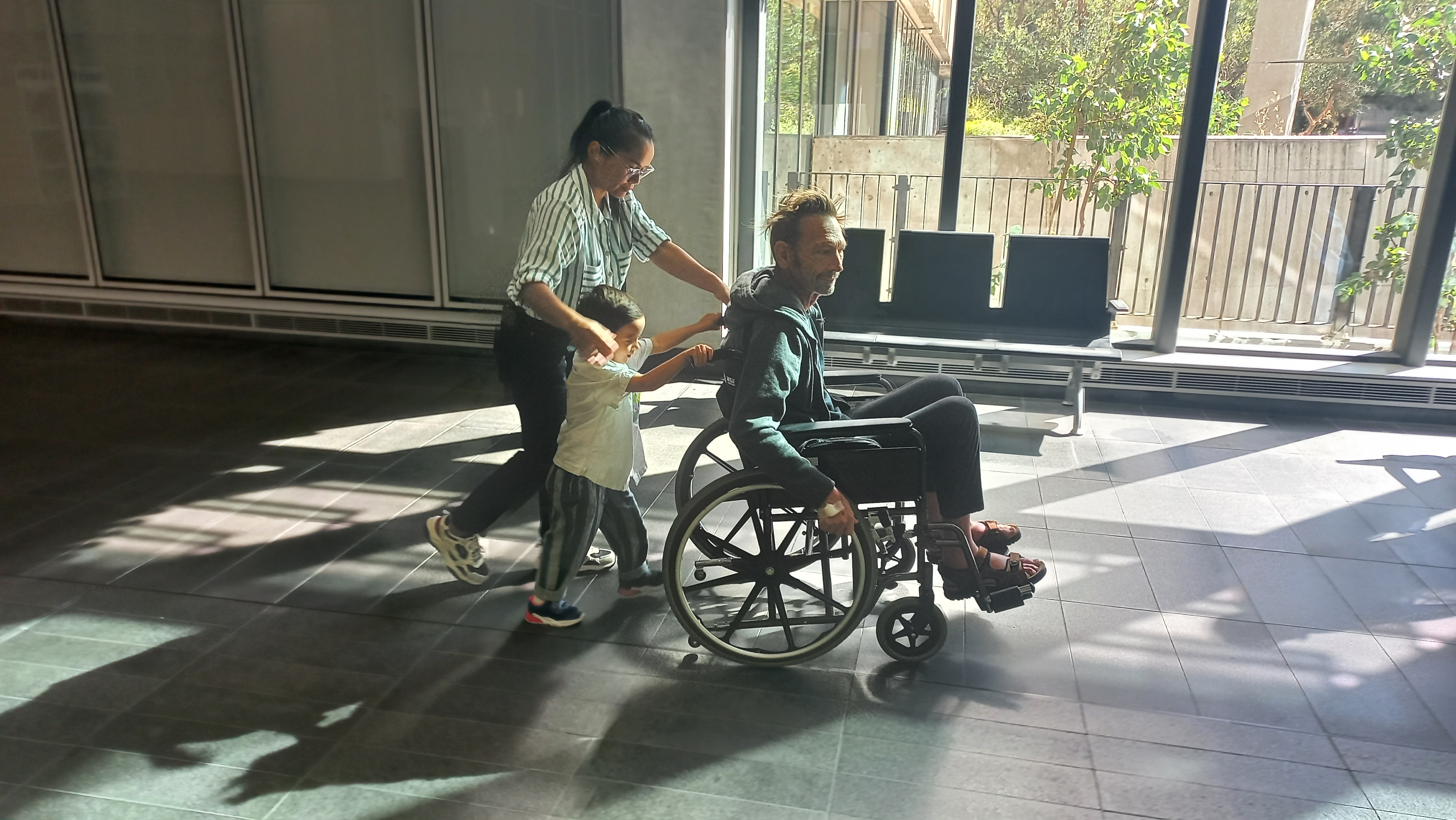Oscar & Tar pushing Michael in wheelchair at Hospital in Perth