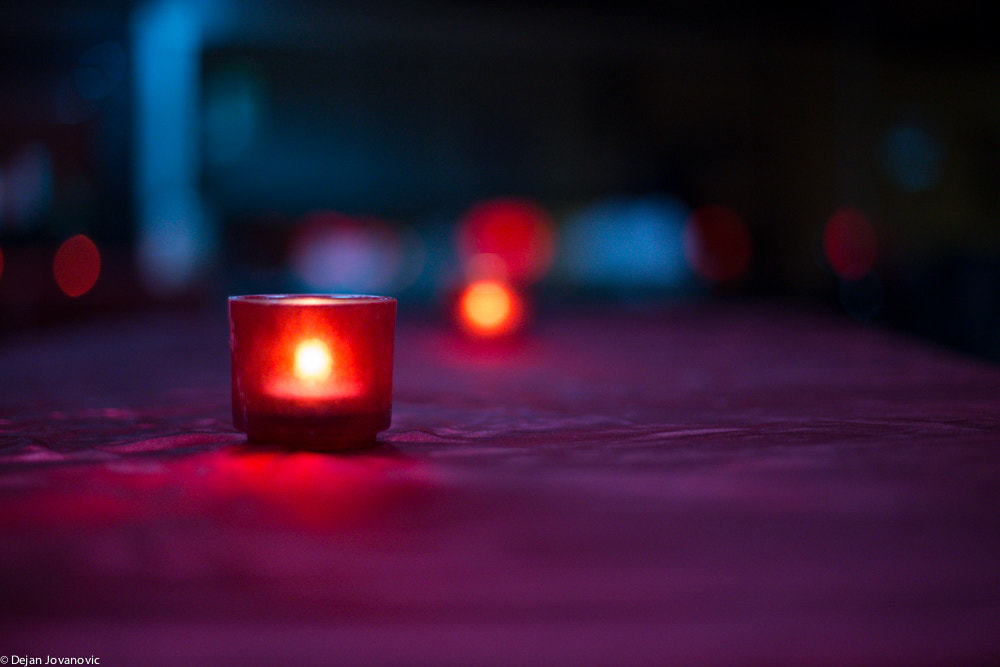Single candle burns in foreground casting a purple hue.